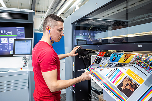 Offsetdrucker zieht Druckbogen aus der Druckmaschine